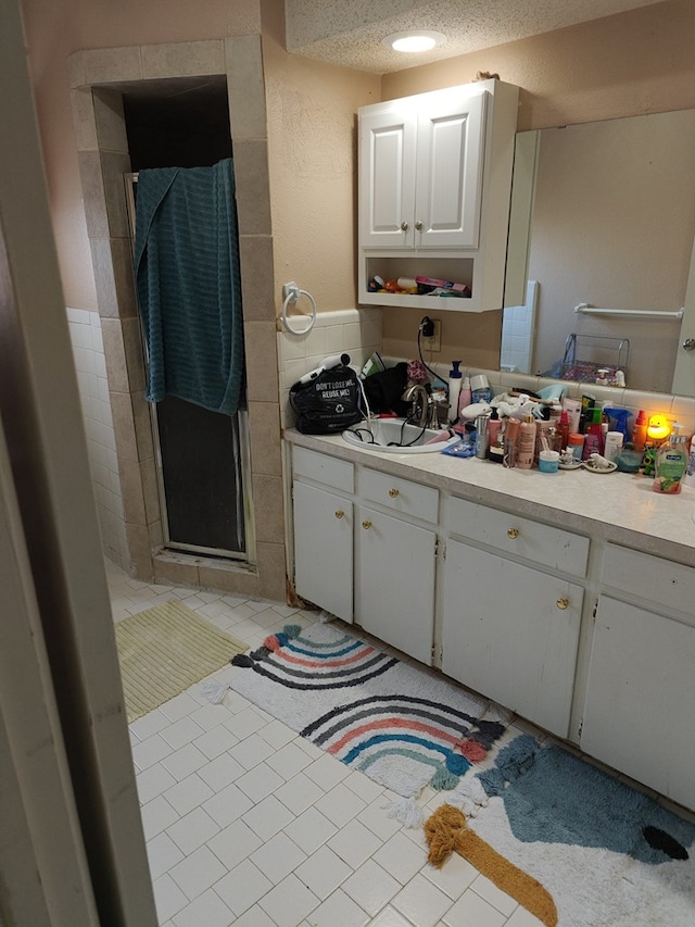 bathroom with tile patterned flooring, vanity, a textured ceiling, and an enclosed shower