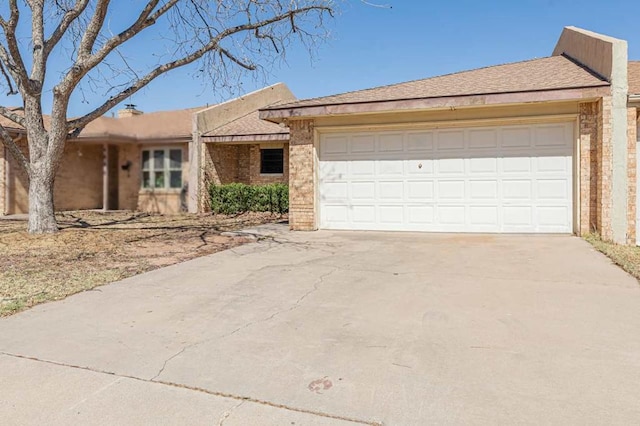 single story home with driveway, brick siding, and an attached garage