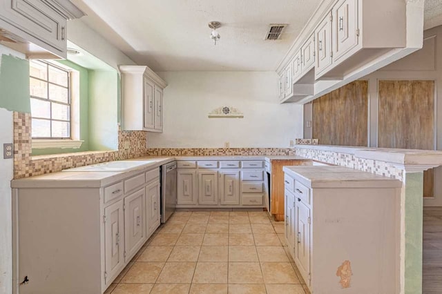 kitchen featuring visible vents, a peninsula, a sink, decorative backsplash, and dishwasher