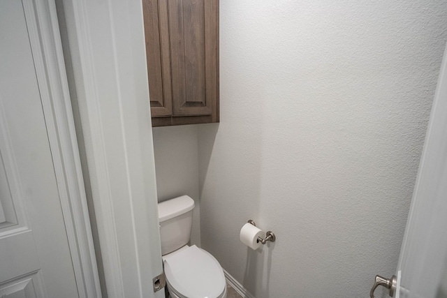 bathroom with toilet and a textured wall