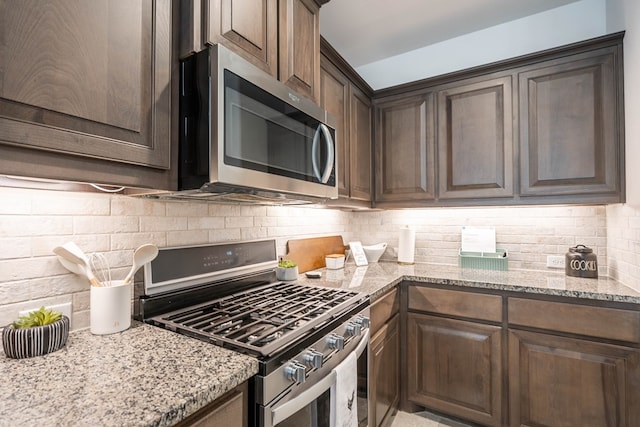 kitchen featuring light stone counters, stainless steel appliances, backsplash, and dark brown cabinets