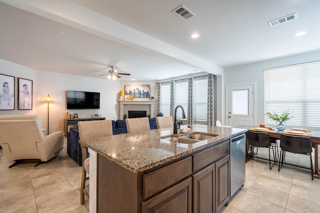 kitchen featuring dishwasher, a kitchen island with sink, visible vents, and a sink