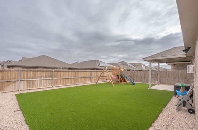 view of yard featuring a patio, a fenced backyard, and a playground