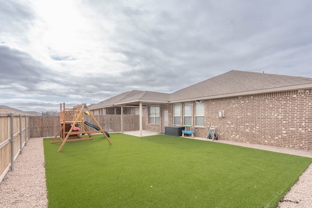 view of yard with a patio, central AC, a fenced backyard, and a playground