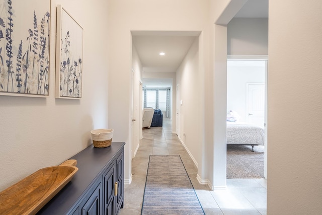 corridor featuring light tile patterned floors and baseboards