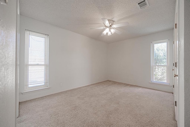 spare room featuring light carpet, a textured ceiling, and ceiling fan