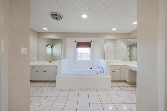 bathroom featuring tile patterned floors, a textured ceiling, vanity, and a washtub