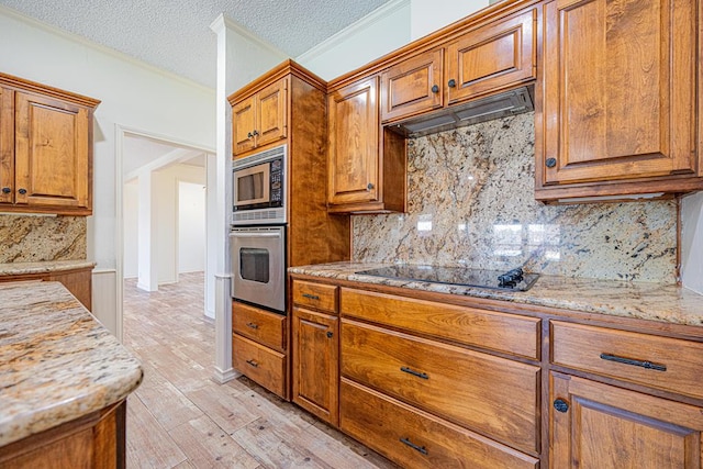 kitchen featuring stainless steel appliances, light stone countertops, custom range hood, and light hardwood / wood-style floors