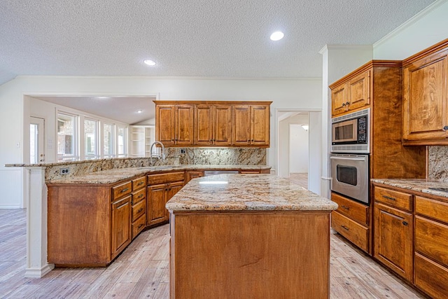 kitchen featuring light stone countertops, sink, stainless steel appliances, and a center island