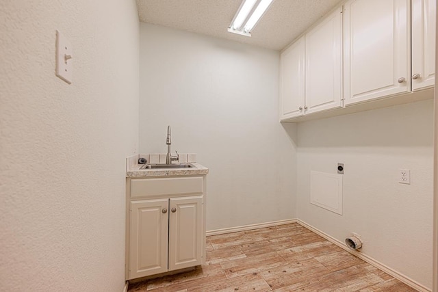 laundry area featuring sink, cabinets, a textured ceiling, hookup for an electric dryer, and light hardwood / wood-style floors