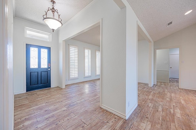 foyer featuring vaulted ceiling, crown molding, a textured ceiling, and light hardwood / wood-style floors