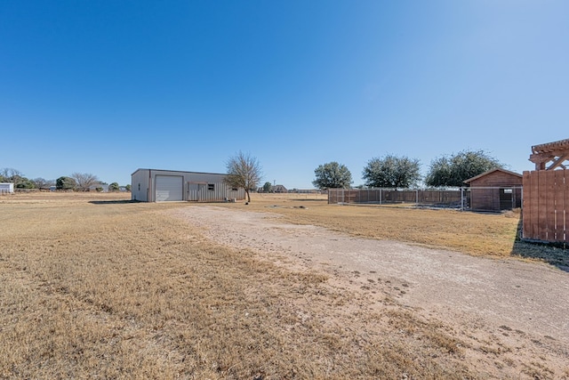 view of yard with a garage, an outdoor structure, and a rural view