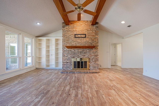 unfurnished living room featuring vaulted ceiling with beams, light hardwood / wood-style flooring, a brick fireplace, and a textured ceiling