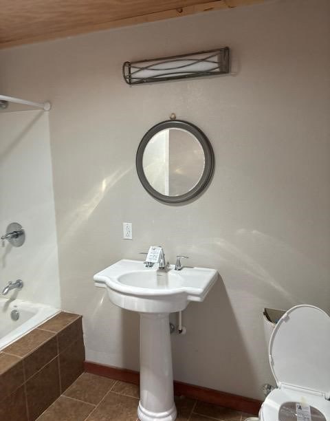 bathroom with tiled shower / bath, tile patterned floors, and toilet