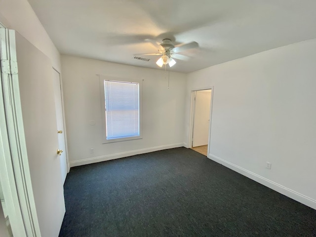 spare room featuring ceiling fan and dark carpet