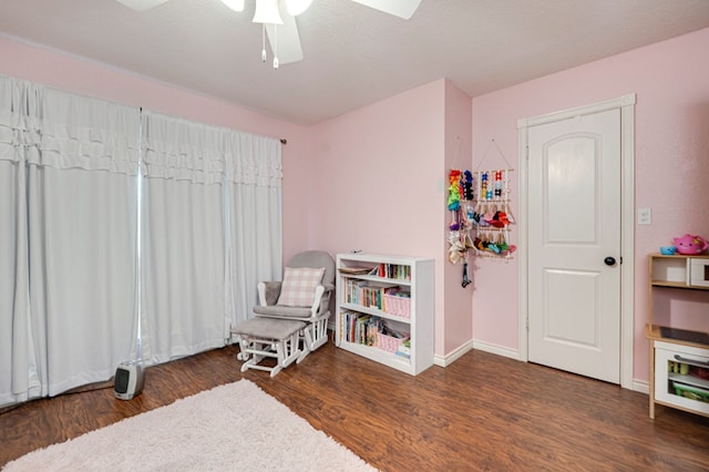 living area with baseboards, a ceiling fan, and wood finished floors