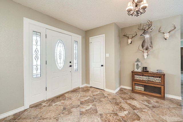 foyer with a notable chandelier, a textured ceiling, and baseboards