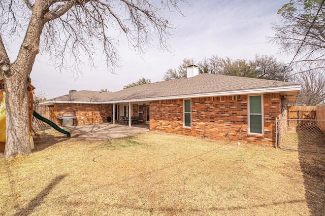 rear view of house featuring fence, a shingled roof, a chimney, a patio area, and brick siding