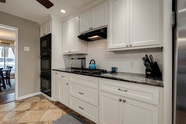 kitchen with tasteful backsplash, under cabinet range hood, dark stone countertops, white cabinets, and black appliances