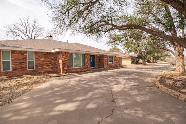 ranch-style house featuring brick siding, driveway, and a shingled roof