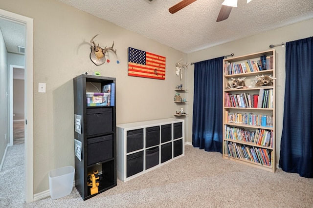 recreation room featuring ceiling fan, baseboards, carpet floors, and a textured ceiling