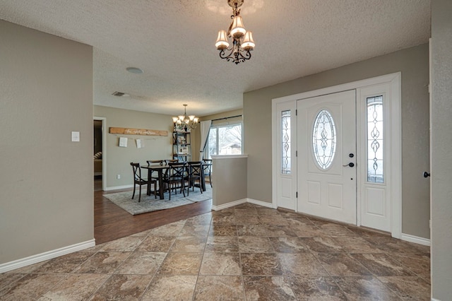 entryway with baseboards, a textured ceiling, and an inviting chandelier