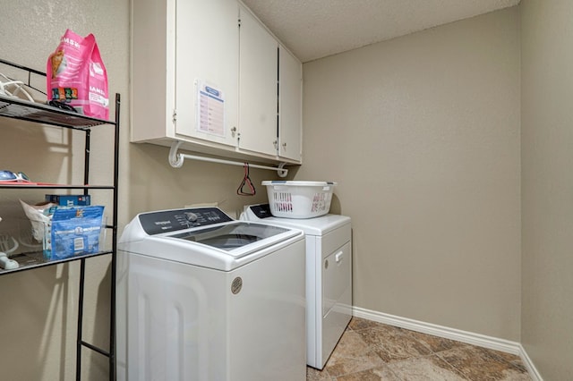 clothes washing area with cabinet space, a textured ceiling, independent washer and dryer, and baseboards