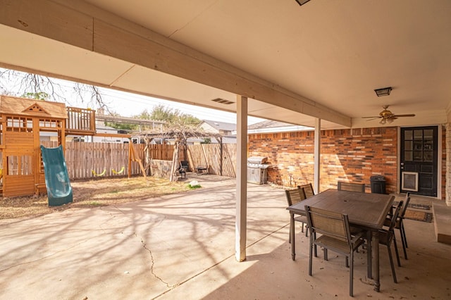 view of patio featuring a playground, fence, outdoor dining area, area for grilling, and a ceiling fan