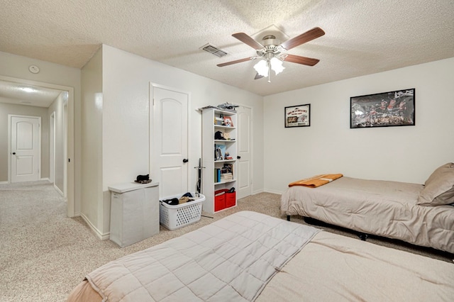 bedroom featuring light carpet, visible vents, a textured ceiling, and baseboards