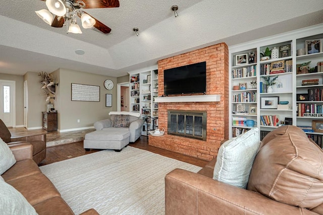 living room with a textured ceiling, a brick fireplace, and wood finished floors