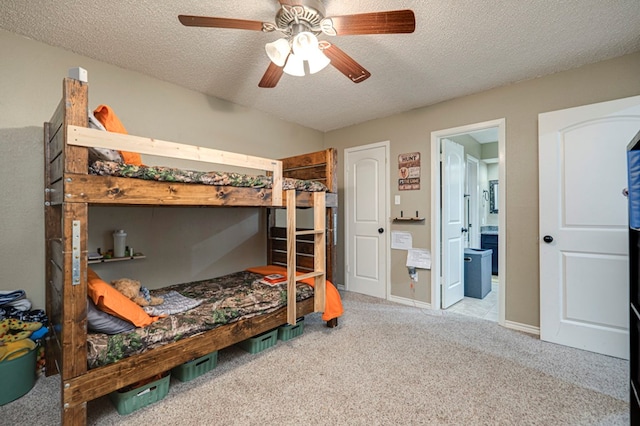 bedroom with a ceiling fan, a textured ceiling, ensuite bath, carpet, and baseboards