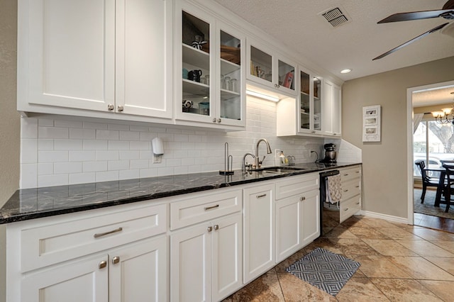 kitchen featuring dishwashing machine, visible vents, a sink, white cabinets, and ceiling fan with notable chandelier