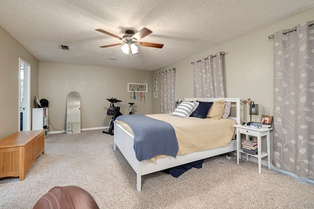 bedroom featuring visible vents, light colored carpet, ceiling fan, and a textured ceiling