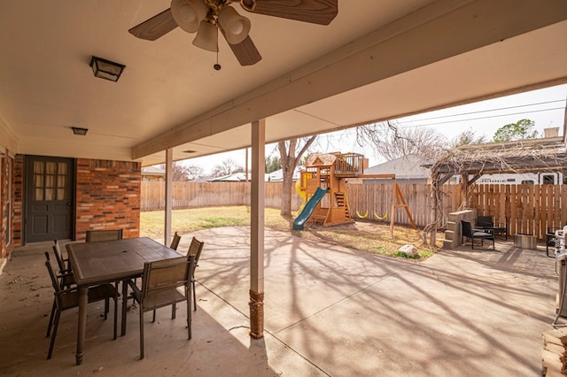 view of patio / terrace with outdoor dining space, a ceiling fan, a playground, and a fenced backyard