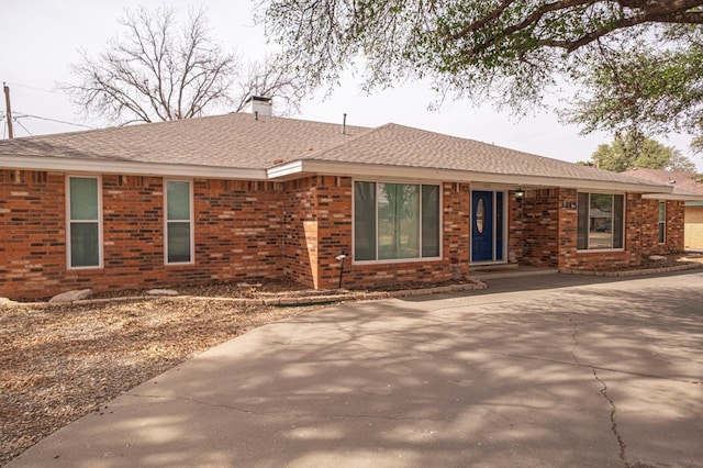 single story home with brick siding, a chimney, and a shingled roof