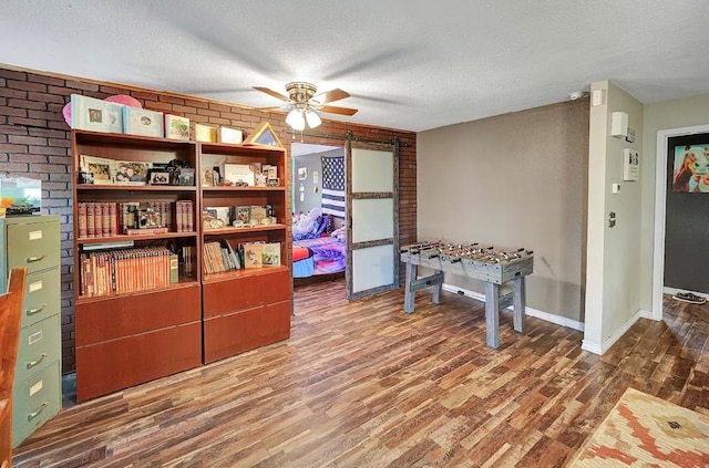 interior space with ceiling fan, wood-type flooring, and a textured ceiling