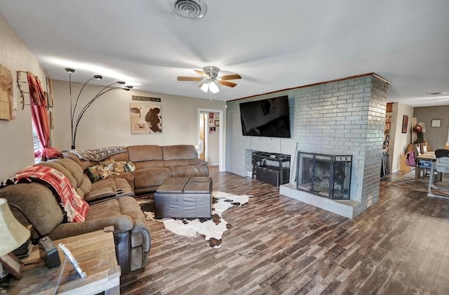 living room with ceiling fan, hardwood / wood-style floors, and a brick fireplace