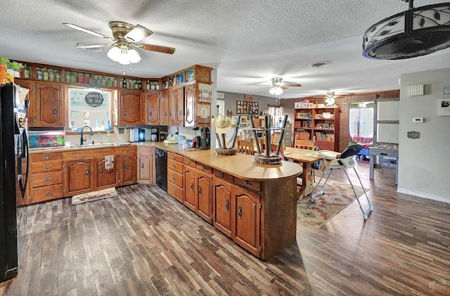 kitchen with a textured ceiling, sink, black appliances, and dark hardwood / wood-style floors