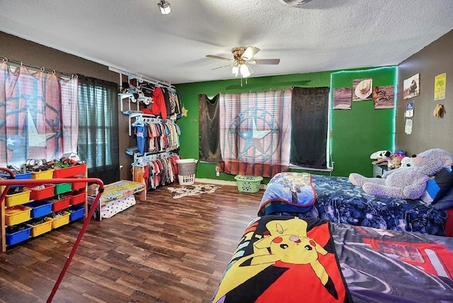 bedroom with ceiling fan, wood-type flooring, and a textured ceiling