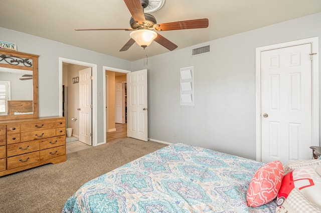 bedroom featuring ensuite bathroom, ceiling fan, and light carpet