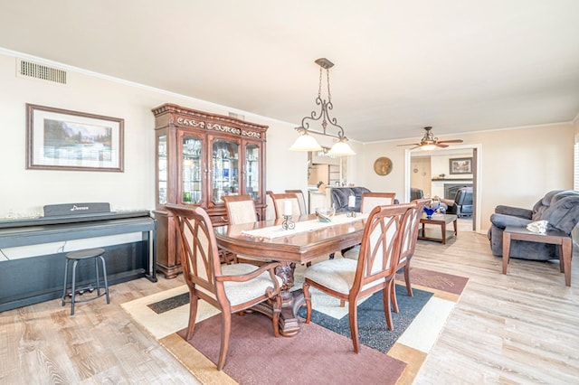 dining room featuring light hardwood / wood-style flooring, ceiling fan, and crown molding