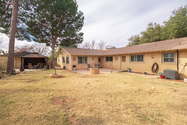 back of house featuring a fire pit, a yard, and central AC