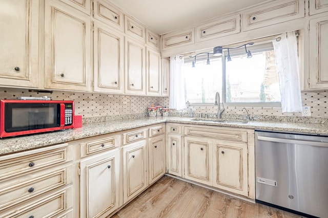 kitchen featuring cream cabinetry, light hardwood / wood-style flooring, stainless steel dishwasher, and sink