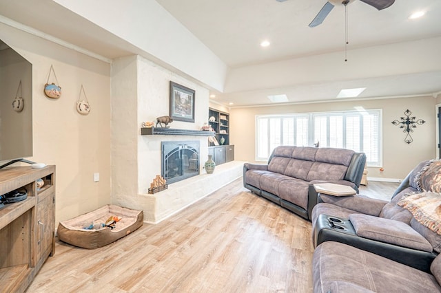 living room featuring ceiling fan, a skylight, and light hardwood / wood-style flooring