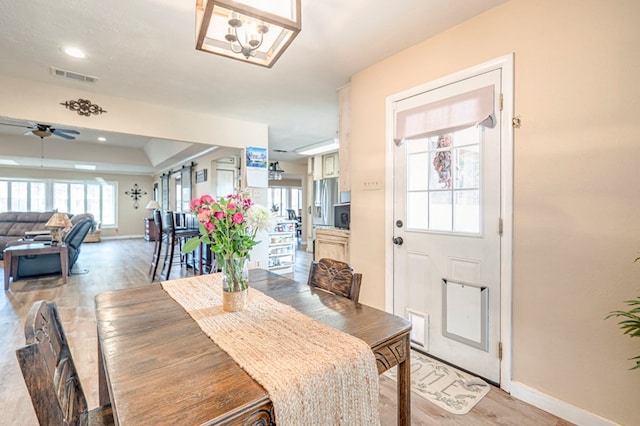 dining area with ceiling fan with notable chandelier and light wood-type flooring