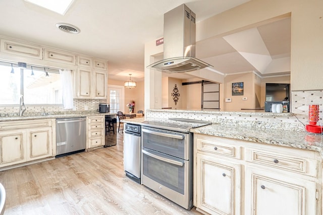 kitchen with appliances with stainless steel finishes, ventilation hood, cream cabinets, and sink