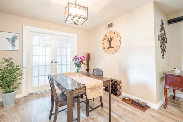 dining room featuring a chandelier, french doors, light hardwood / wood-style flooring, and plenty of natural light