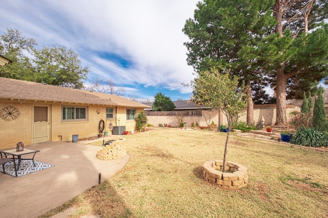 view of yard with a fire pit, central AC unit, and a patio