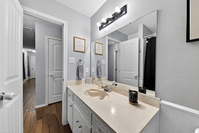 4901 Chon Cv, Midland, TX 79707 - full bathroom with wood finished floors, vanity, wainscoting, and a textured wall
