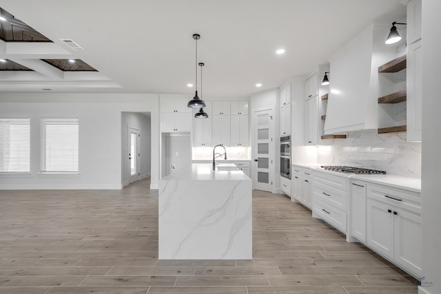 kitchen featuring plenty of natural light, light stone counters, white cabinetry, and sink